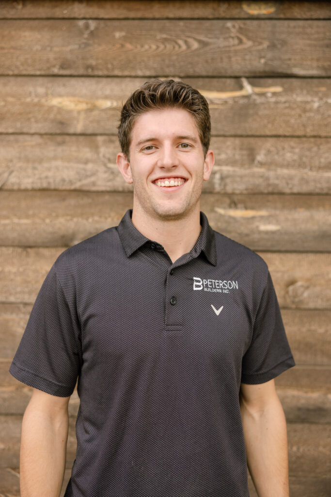 Ryan Peterson, Preconstruction Manager at Peterson Builders Inc., smiling in a branded polo shirt against a wooden background.